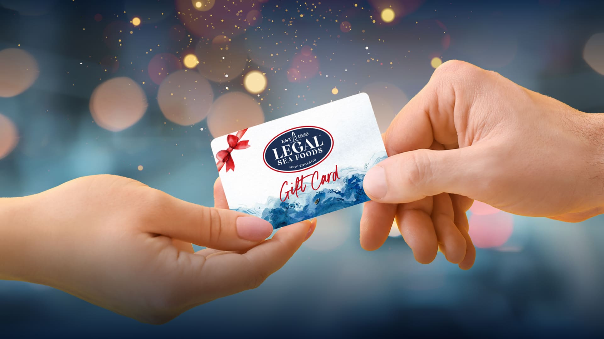 Two hands exchanging a gift card for a seafood restaurant. The card features a red bow design and is set against a festive, blurred background with warm bokeh lights.